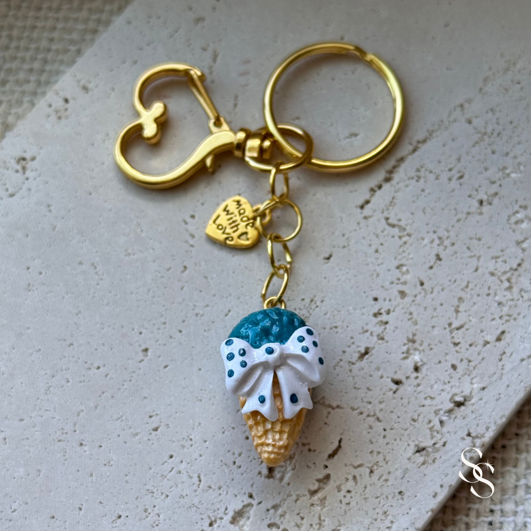 Keychain with ice cream cone charm and gold clasp on a textured surface