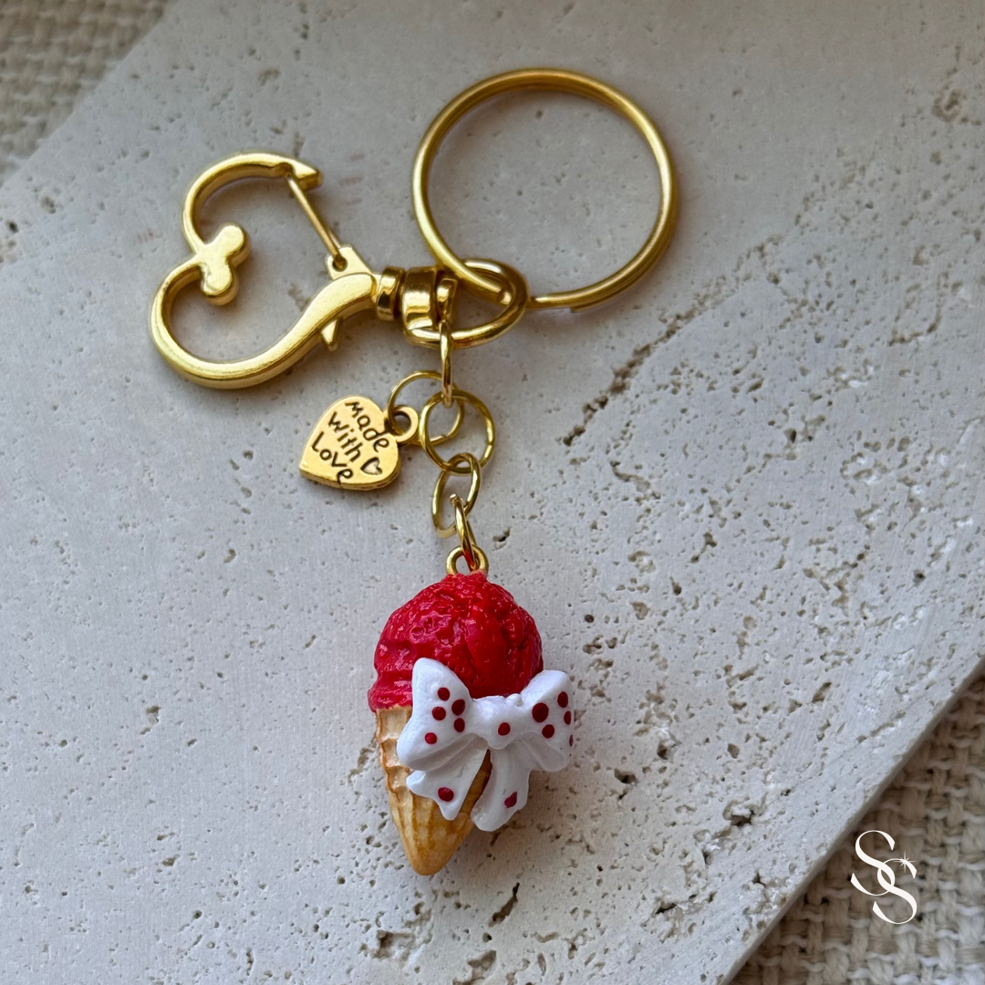 Keychain with ice cream cone charm and gold clasp on a textured surface
